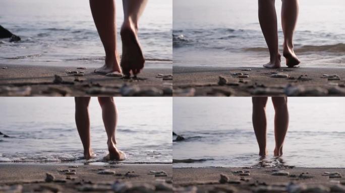 从裸露的膝盖后面射击-人类的双腿缓慢行走，朝着大海的方向测量步数，然后进入脚踝深处。这个人停下来站在