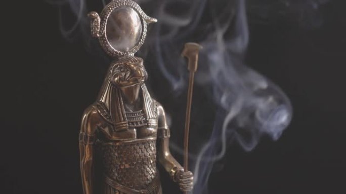 黑色背景上烟雾中的埃及神拉的金色雕像