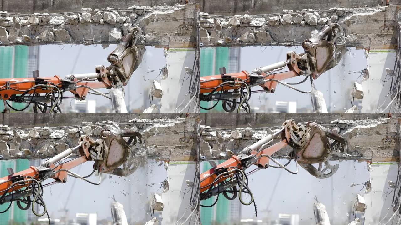 一台大型机器正在使用大钳在建筑工地中分解水泥墙。