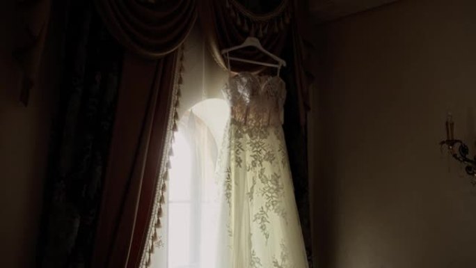 新娘的婚纱挂在房间窗户的背景上