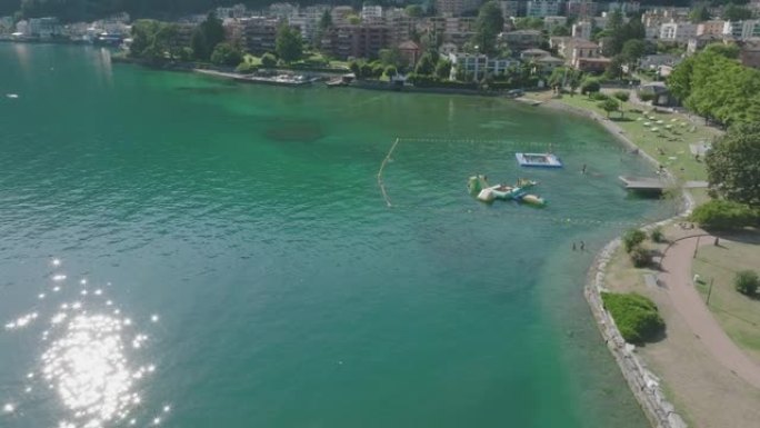 空中无人机景观沿着湖岸的海滩，人们在水中游泳