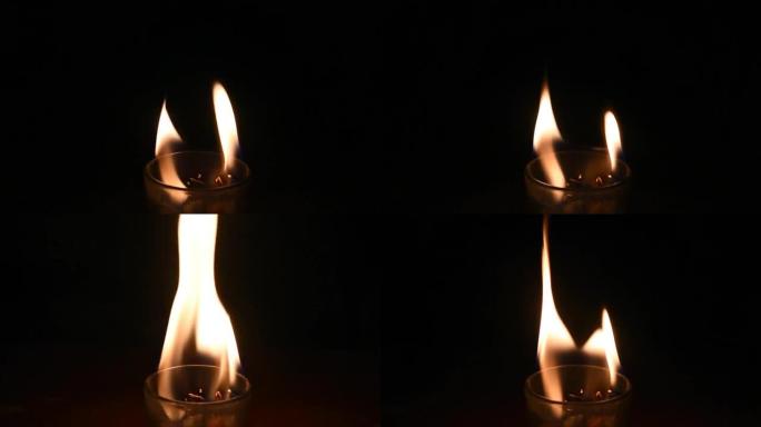 在黑暗背景包围的玻璃中燃烧蜡烛火焰