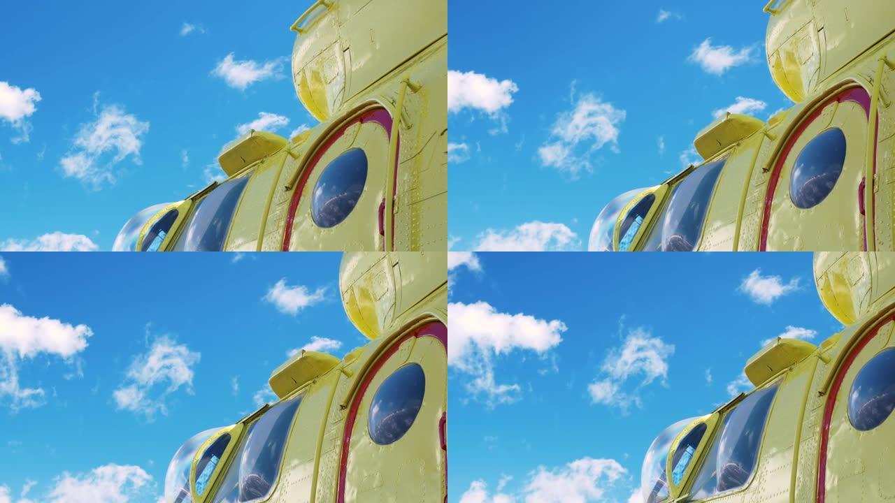 黄色直升机，红色框门，鼓鼓囊囊的窗户。一架亮黄色的直升机映衬着偶尔有小朵云的蓝天。凸窗和直升机水泡。