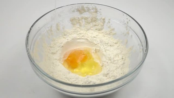 鸡蛋慢慢落入一碗面粉中，慢动作