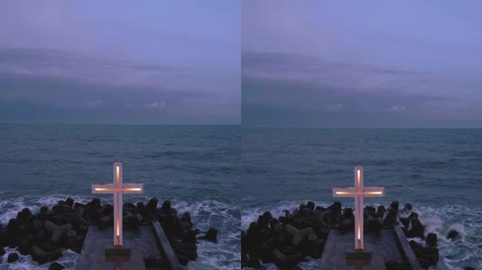 基督教十字架站在海上或海洋的码头上，夜晚有戏剧性的天空