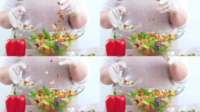 在新鲜沙拉中添加坚果素食杏仁榛子腰果围裙特写仅手美味饮食减肥健康生活方式蛋白质和碳水化合物红辣椒前景
