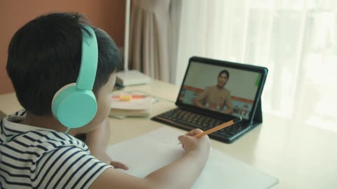 亚洲男孩正在在家参加在线课程。