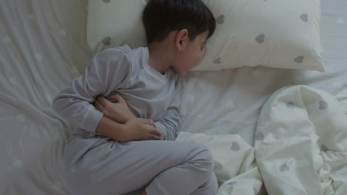 亚洲男孩躺在床上胃痛的俯视图