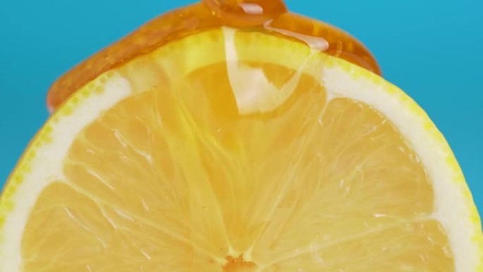 蜂蜜从蓝色背景上的新鲜柠檬片上滴下来的宏观纹理照片。