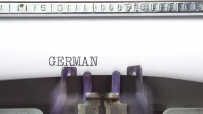 德国文字特写正在打字，并以老式打字机机械的一张纸上为中心