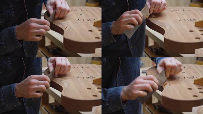 吉他制造商使用刮刀工具在车间中平滑雕刻吉他主体的背面