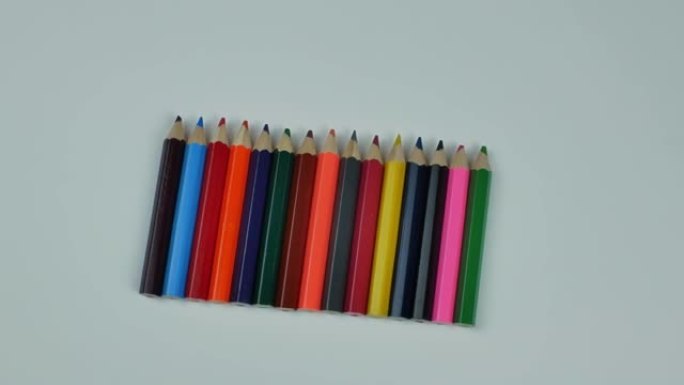 浅色背景上的一组多色木制铅笔。一组彩色木制铅笔排成一排。平躺，从上面看正视图。一套绘画铅笔的概念