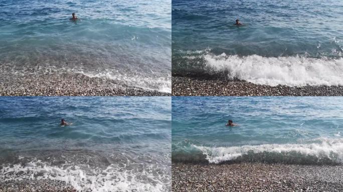 快乐的成年男子在海浪中的蓝色水中游泳。视频9秒
