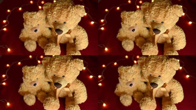 一对泰迪熊正坐在红色针织格子和灯泡花环的背景下。情人节