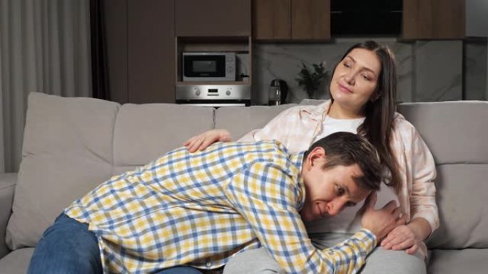 丈夫爱抚坐在沙发上的妻子怀孕的肚子