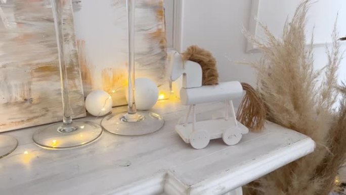 壁炉上的木马，大厅里有蜡烛。米色、金色和白色的发光气氛灯和球