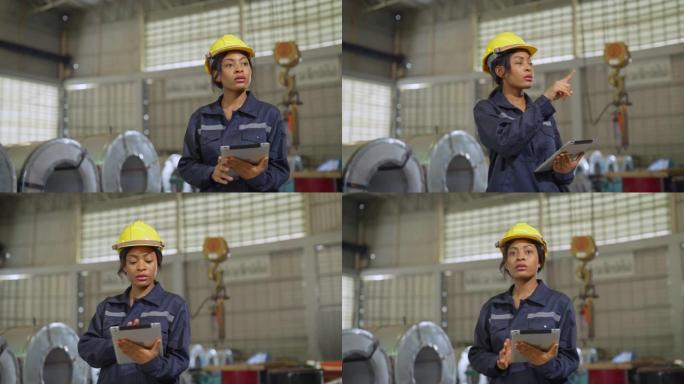 在一家重工业制造工厂，戴着安全帽和安全套工作机的女工业工程师。