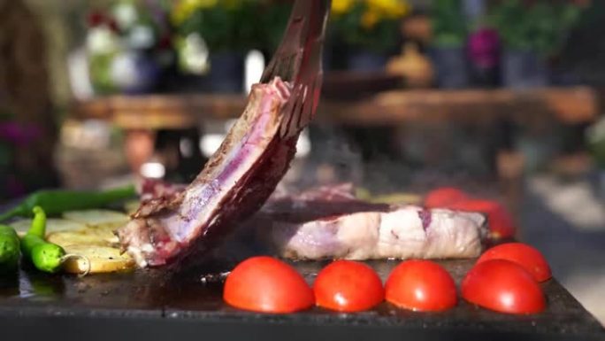 煮熟的多汁牛排牛肉，用迷迭香刷在燃烧的烤架上，周围是其他肉和香肠。