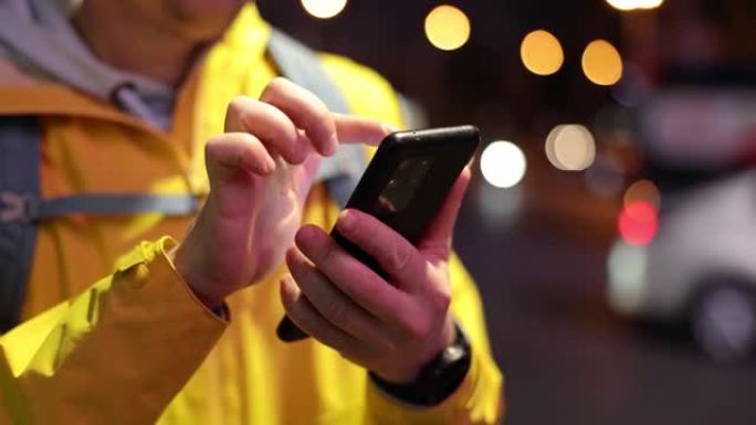 男性快递员在夜间街头通过互联网在手机中寻找信息特写4k电影慢镜头