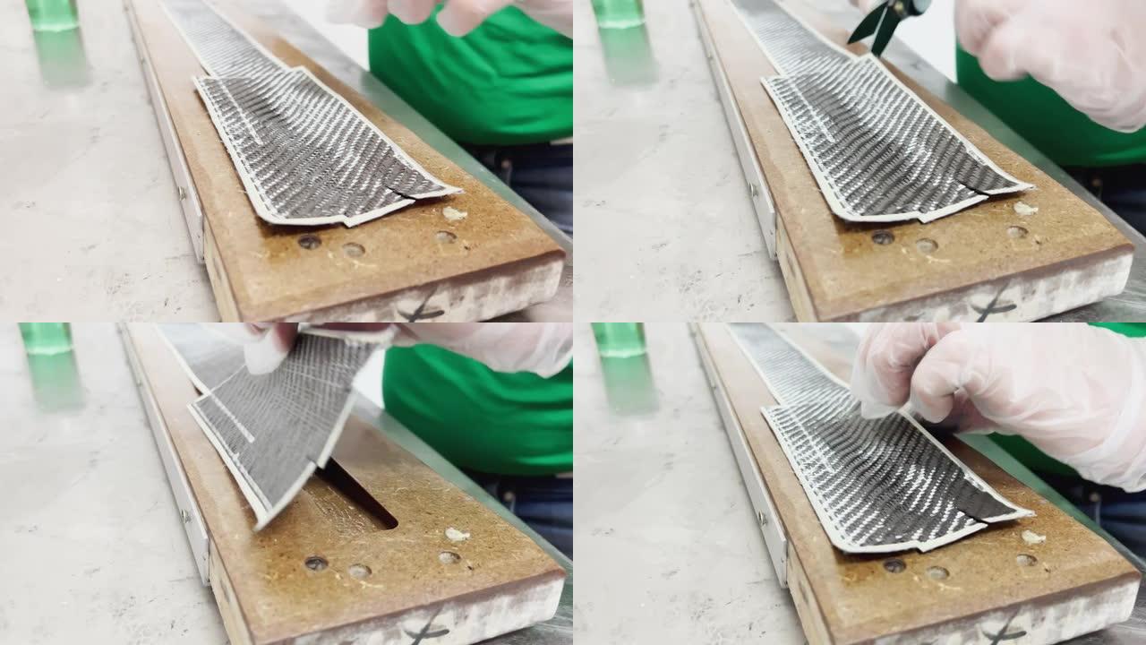 一名防护手套专家在烤盘上铺了一层碳布，并切割，碳纤维条，木材压榨机模具