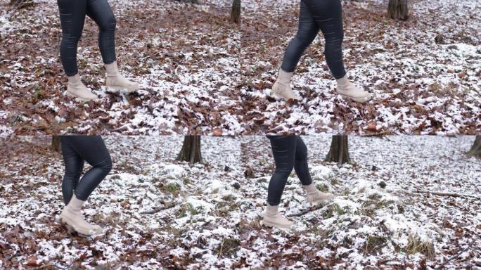 冬天森林里的女人。穿着紧身皮裤和靴子的人的腿沿着雪公园行走，相机向右移动。女人悠闲地在树上的白色湿雪