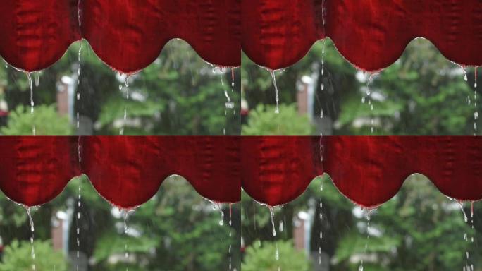 从红色窗帘流下的雨滴特写
