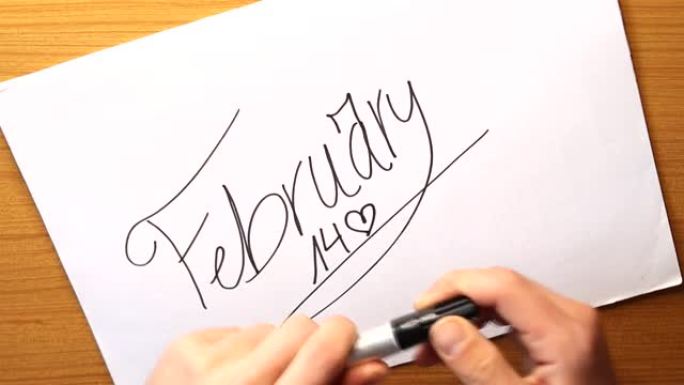 一个人的手覆盖着一支记号笔，并将其放在一张纸上，上面写着情人节2月14日