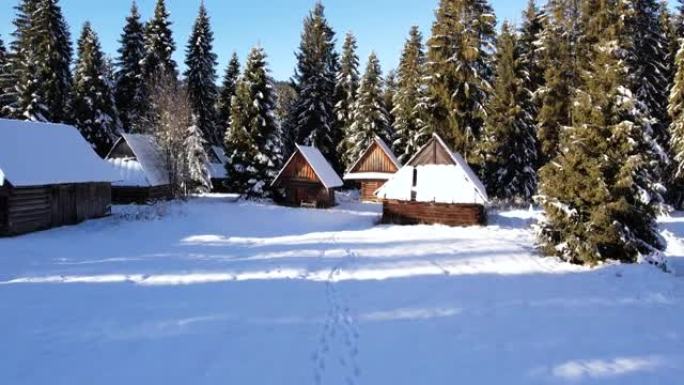 山里白雪覆盖的小屋的鸟瞰图。雪白的冬天风景。美丽的山间小屋或小屋在冬季森林中被雪覆盖。