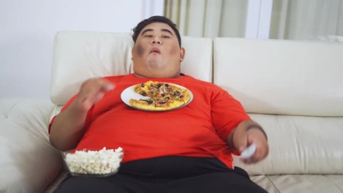 肥胖男子在家吃零食时看电视
