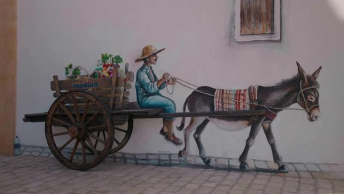 用驴子拉的雄性在手推车的墙上画画。