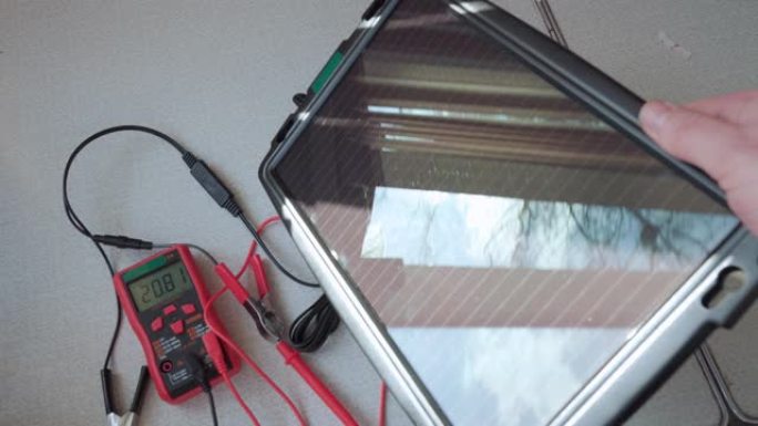 一个小的太阳能电池板连接到一个测试仪来测量输出电压。