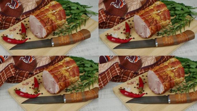 一块多汁的猪肉火腿放在木制切菜板上，旁边是一把雕刻刀、多色五香豆、红辣椒、欧芹、莳萝和罗勒。美味肉制