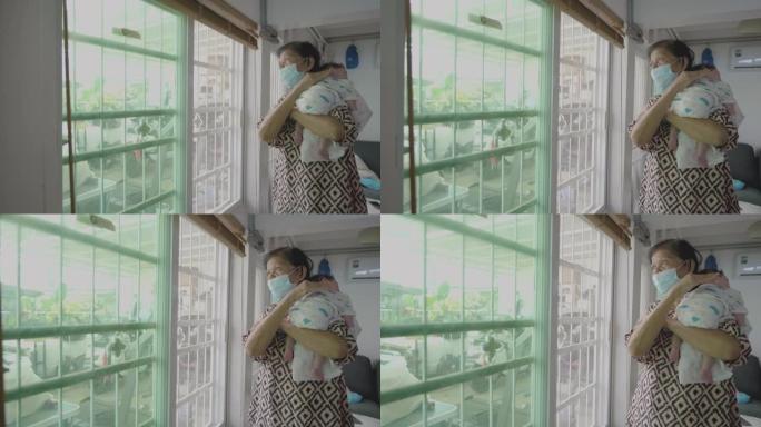 亚洲祖母在家戴口罩抱孙子。