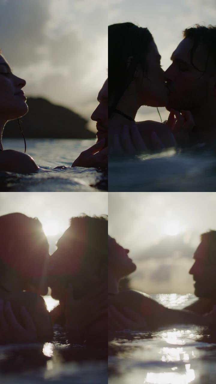 浪漫的异性恋夫妇在日落时一起在海里游泳。拥抱和亲吻在水中一起垂直视频