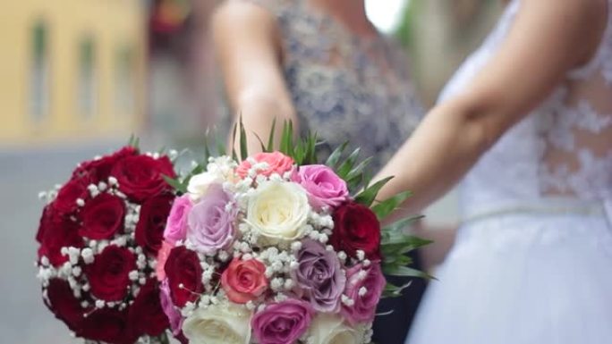 新娘和教母在拍照时一手握住花束