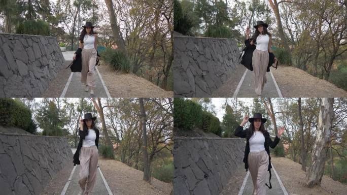 一个西班牙裔模特戴着帽子在公园走秀的漂亮4k镜头