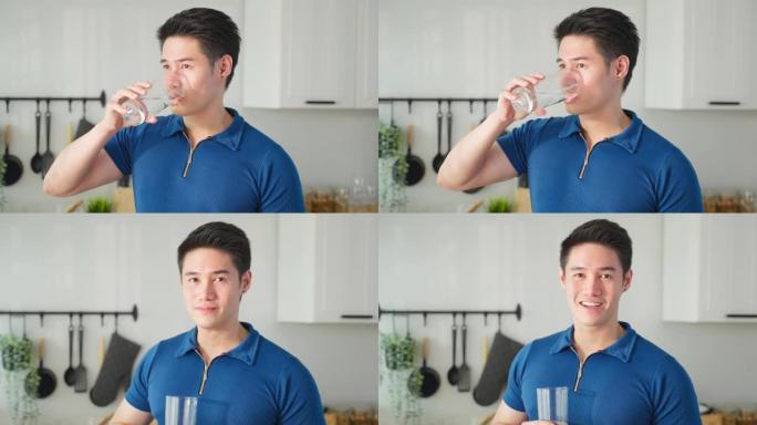 亚洲活跃强壮男子在厨房喝干净的水的肖像。有吸引力的口渴的男性将水倒入玻璃杯中，醒来后喝一口天然矿物质