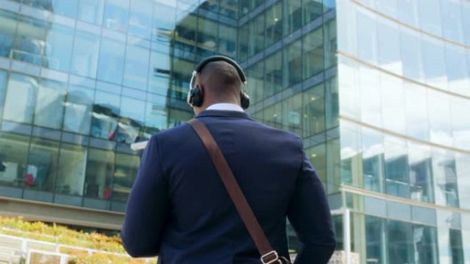 一个非裔美国年轻有魅力的男人在街上走路的手机的后视图听音乐