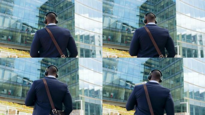 一个非裔美国年轻有魅力的男人在街上走路的手机的后视图听音乐