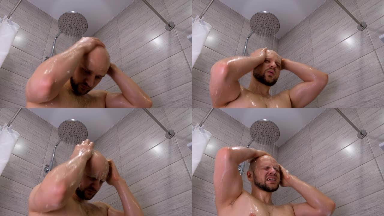 一个留着胡须的肌肉发达的秃头男人在淋浴下的浴室里洗漱，将肥皂和洗发水涂在身上，然后洗掉