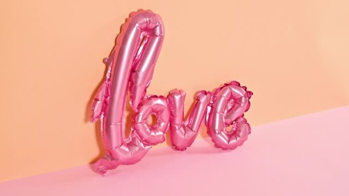 爱情浪漫情人节气球出现在橙色粉色柔和主题上。停止运动