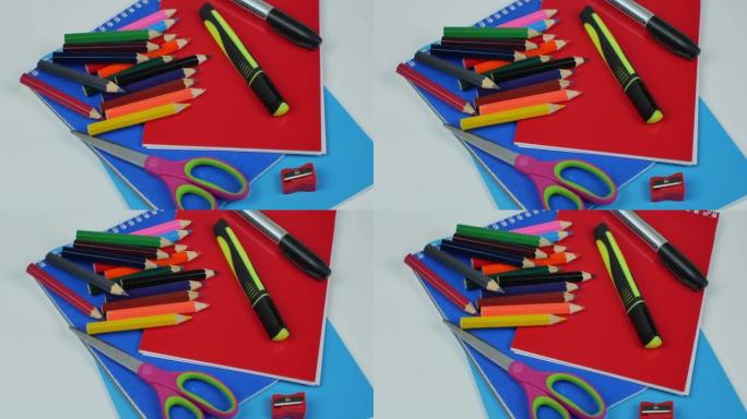 在灰色背景下为儿童的创造力设置。彩色木铅笔，黄色和灰色记号笔，卷笔刀，彩纸，笔记本，办公室剪刀。办公