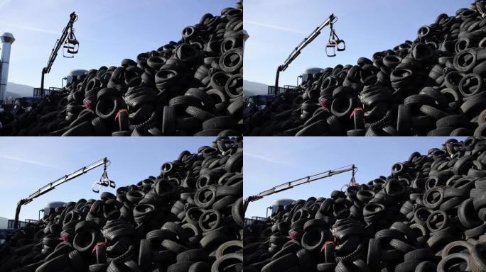 起重机钩在垃圾填埋场捡起堆叠的轮胎