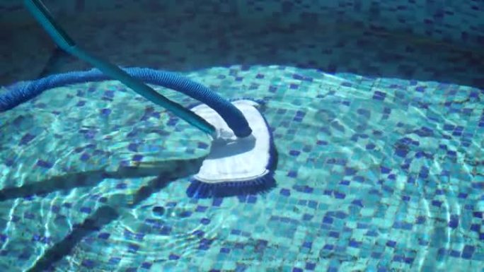 用吸尘器吸住游泳池肮脏的底部。带有条纹软管的特殊刷子可以清洁游泳池。在水下水池中工作的清洗机软管