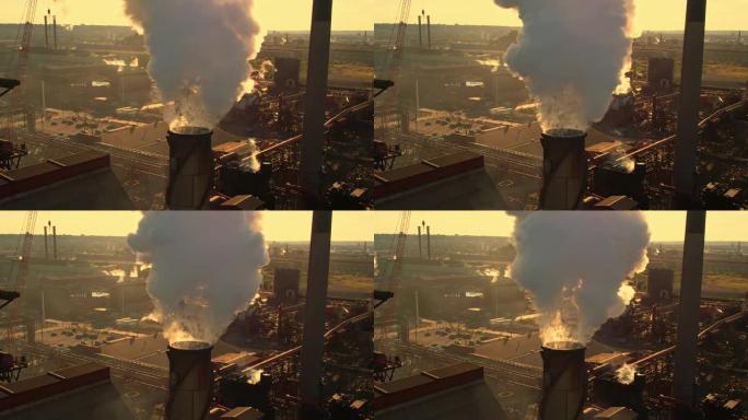 日落时间和黄金时段的钢厂管道。浓烟背后的阳光。冶金厂和烟云来自烟囱，形成温室气体区层。气候变化。