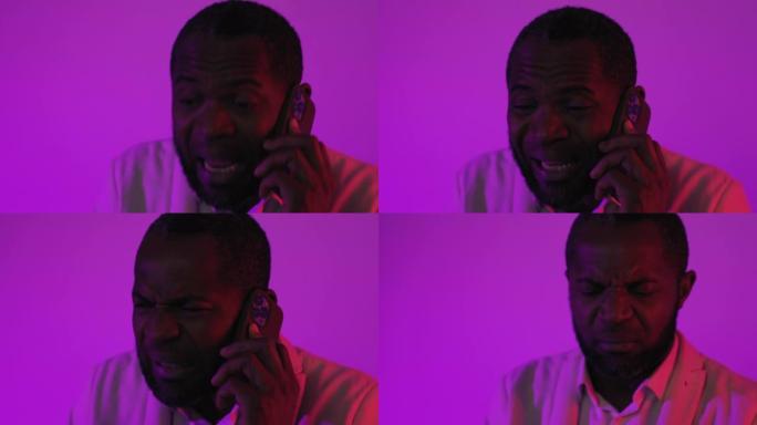 黑人坐在智能手机上聊天。非裔美国人在演播室通过电话吵架挂断了电话。紫罗兰色洋红色背景。特写镜头
