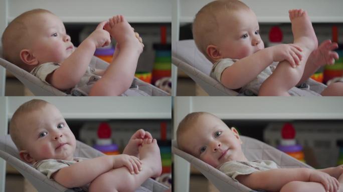 男婴抱着他的赤脚，10个月大的高加索孩子在婴儿摇椅上玩他的赤脚特写