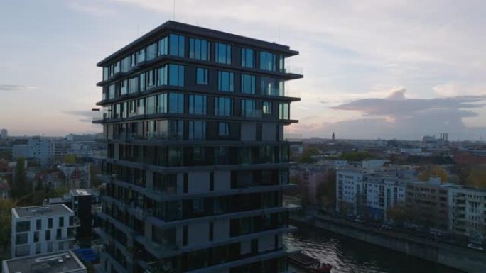空中轨道拍摄在河岸上的现代高层公寓楼周围。日落时住宅城市自治市镇。德国柏林