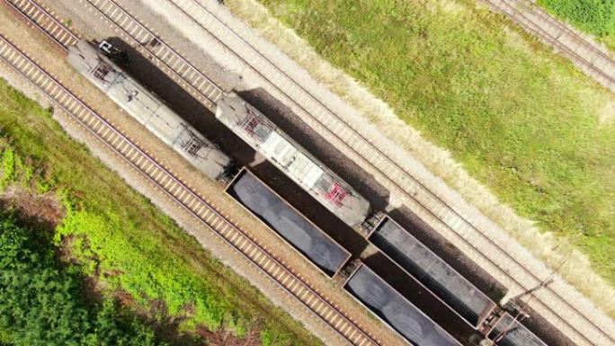 铁路货运列车货车在铁路上行驶。集装箱货物的运输和交付。在河流和燃煤电厂附近乘坐火车的鸟瞰图。