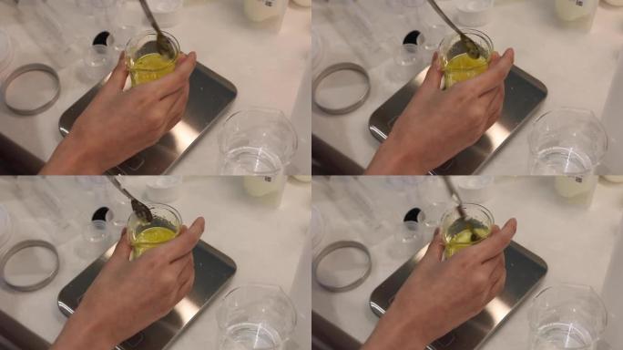 用勺子混合烧杯中的油和蜂蜡，在实验室的电子秤上称量配料